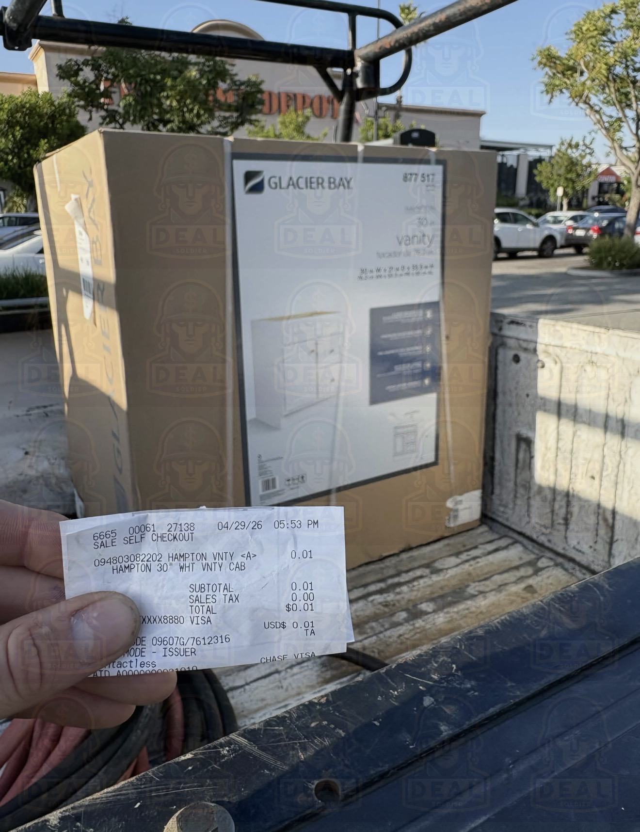 Glacier Bay Hampton 30 inch white vanity cabinet box loaded into the bed of a pickup truck in front of a Home Depot store, with a hand holding a receipt confirming a $0.01 total.
