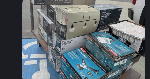 Home Depot flat cart in a parking lot loaded with boxed Hampton Bay Florabelle and Myles island chandeliers, two Makita X-LOCK cordless angle grinders, and a stack of hexagon mosaic wall tile.