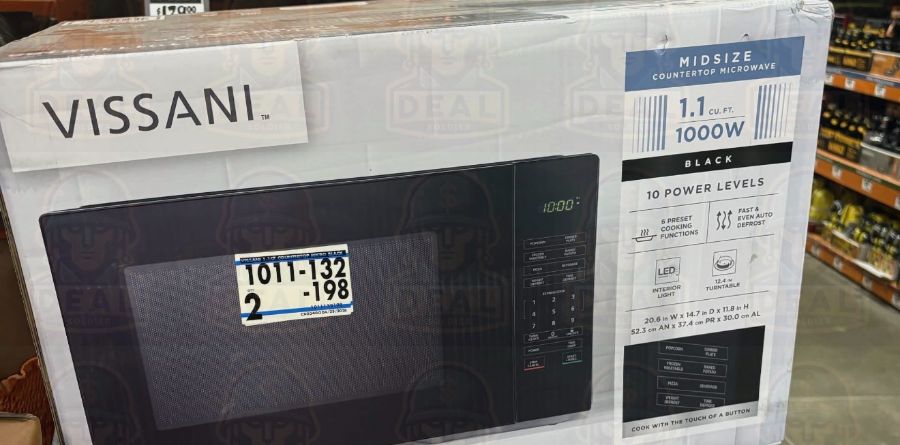Two boxed Vissani 1.1 cu. ft. countertop microwaves stacked on a Home Depot orange cart inside the store, the top box carrying a printed shelf tag reading 1011-132-198 with a quantity of 2.