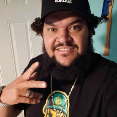 Deal Soldier member in a black Deal Soldier cap and logo tee throwing a peace sign